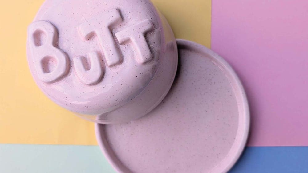 a pink butter dish with the text BUTT on it