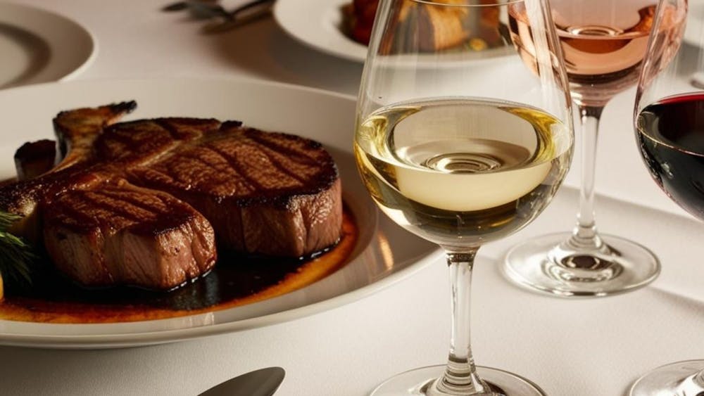 A steak dinner with three glasses on wine on the table
