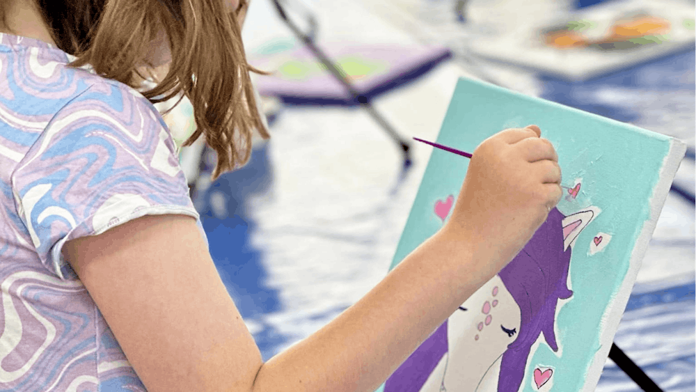 Child painting a unicorn canvas