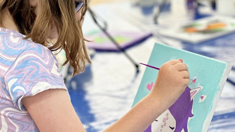 A young girl painting a canvas at The Art Club Hub