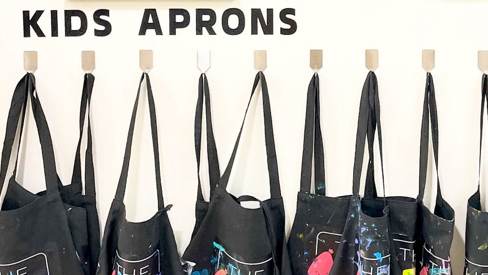 A row of child aprons ready to be used for painting at The Art Club Hub