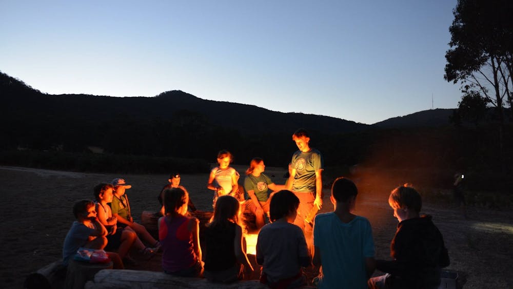 Campers hanging out around the campfire at sunset