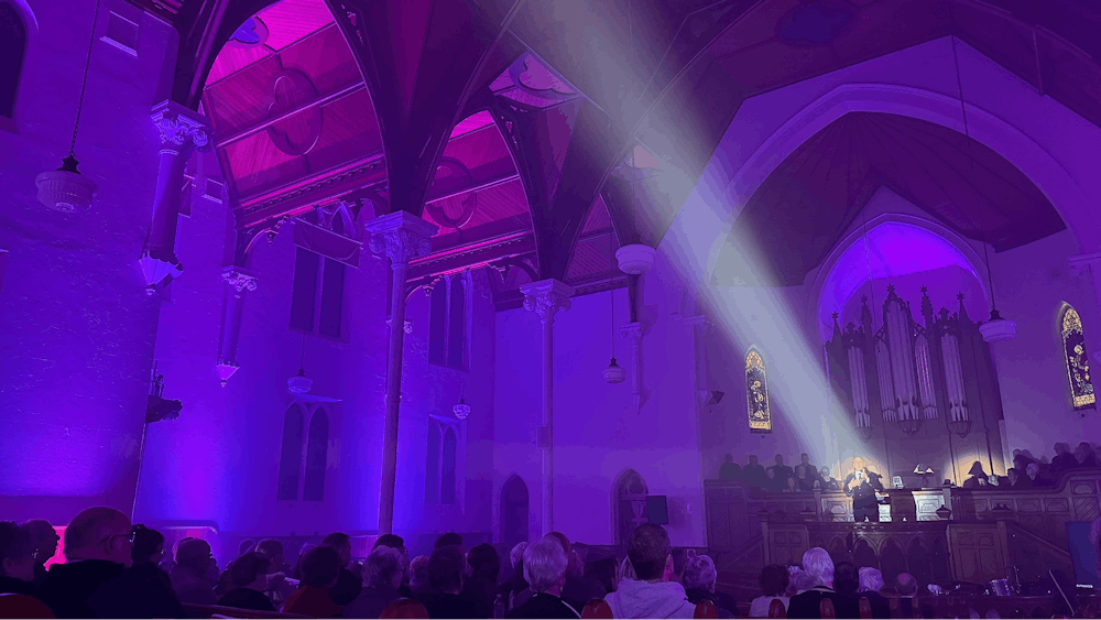 A chapel interior with purple lighting and a performer in a spotlight