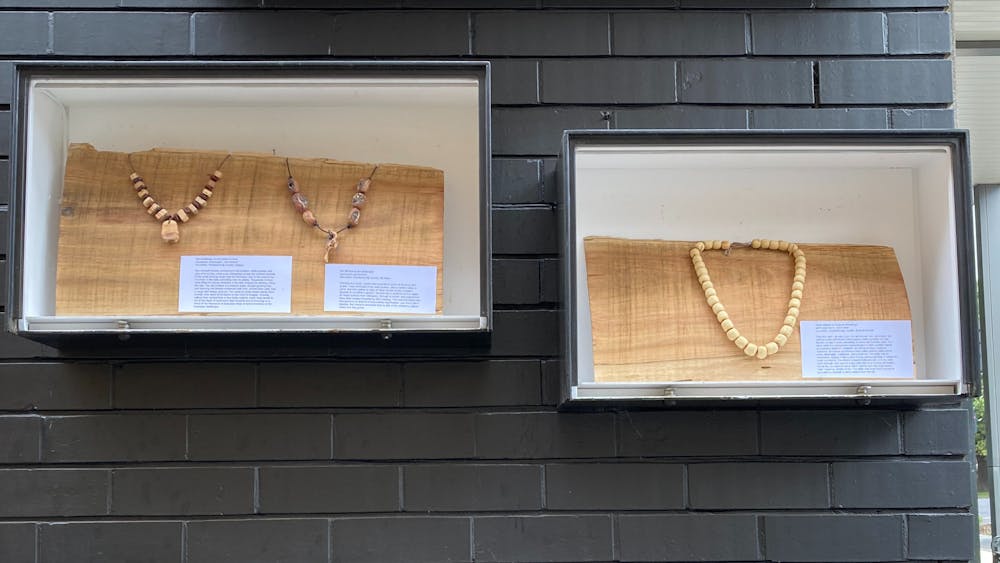 Handmade beads created from seed pods exhibited on wood boards in display boxes.