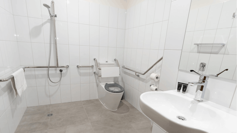 Accessible bathroom with shower, toilet rails, and sink designed for mobility access.