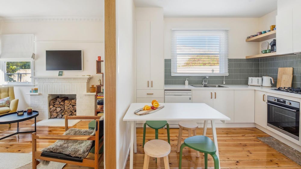 Kitchen table, stools, sink and part of loungeroom with TV