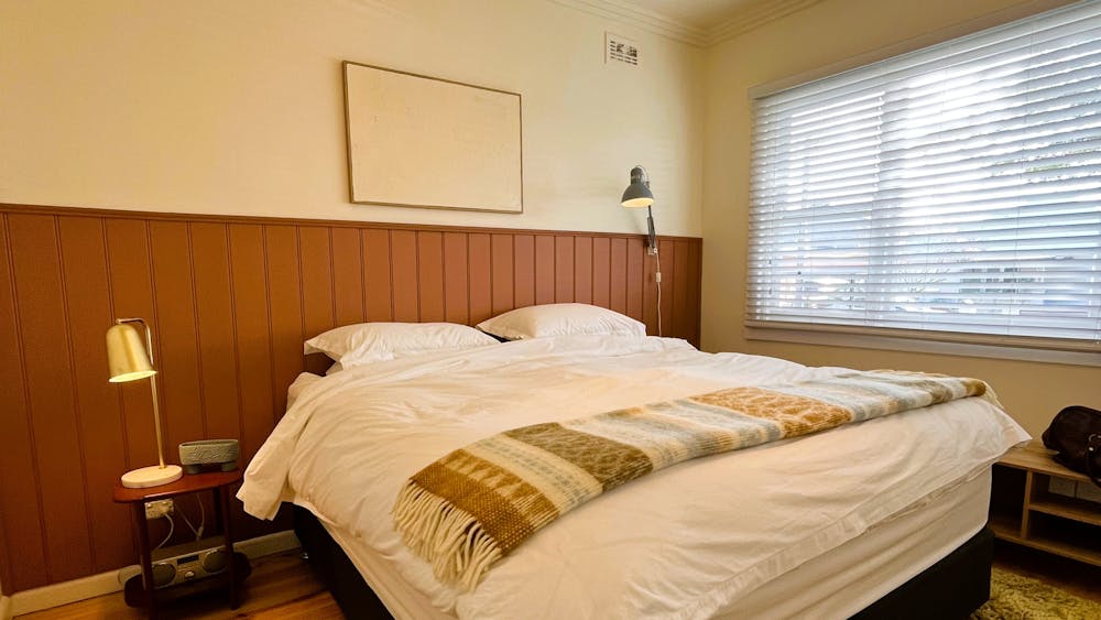 King bed, blankets, artwork, window.