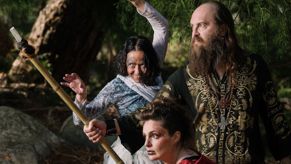 Three characters in intricate clothing, one holding a staff