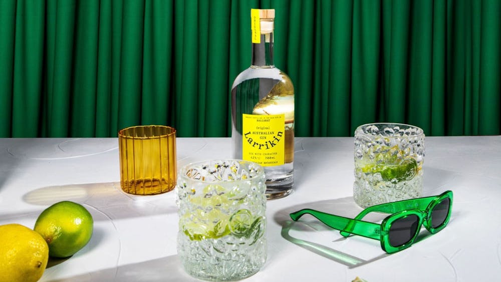 A table with a bottle of gin, two glasses, lemons, limes and sunglasses