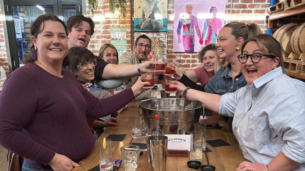 A group of people holding up their drinks and smiling at the camera