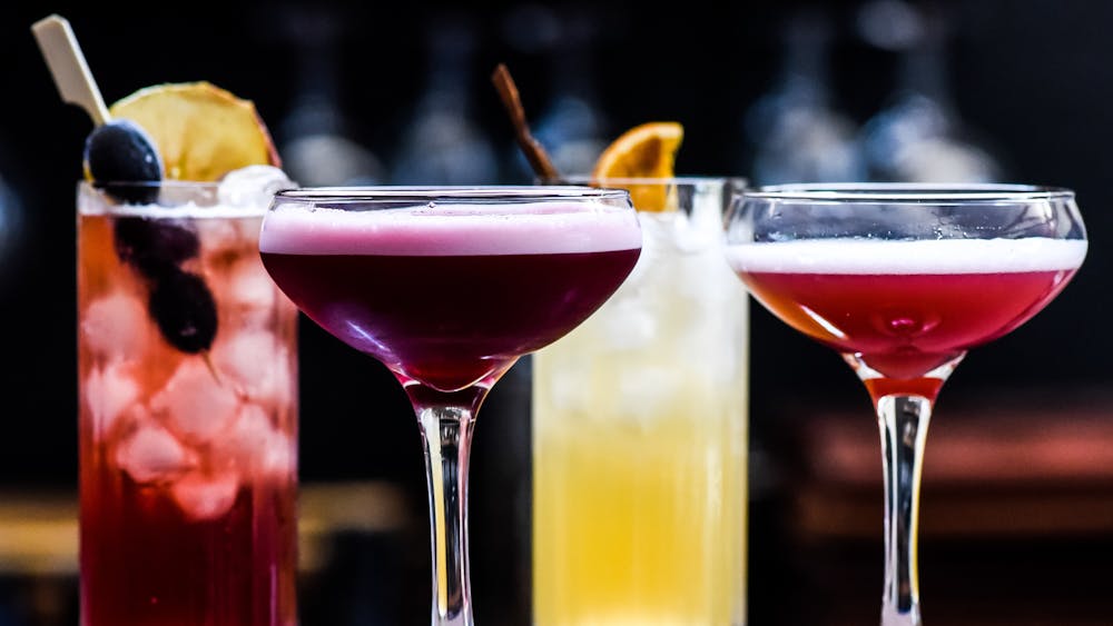 a row of four different colourful cocktails
