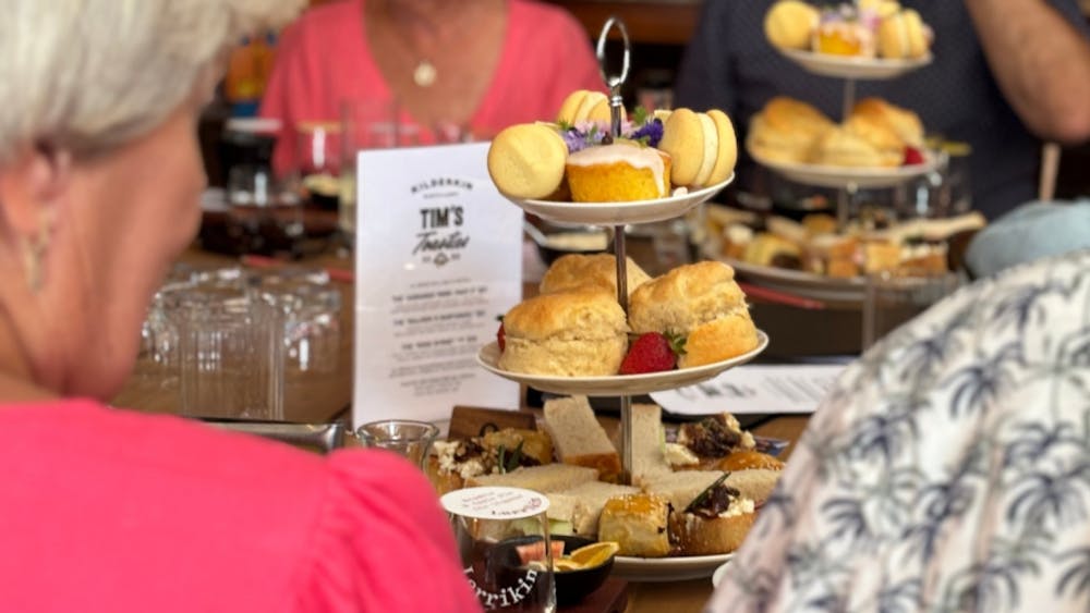 A tower of sweet and savoury treats on a table surrounded by people
