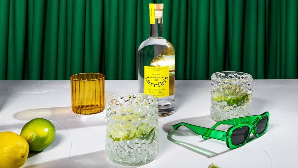 A table with a bottle of gin, two glasses, lemons, limes and sunglasses