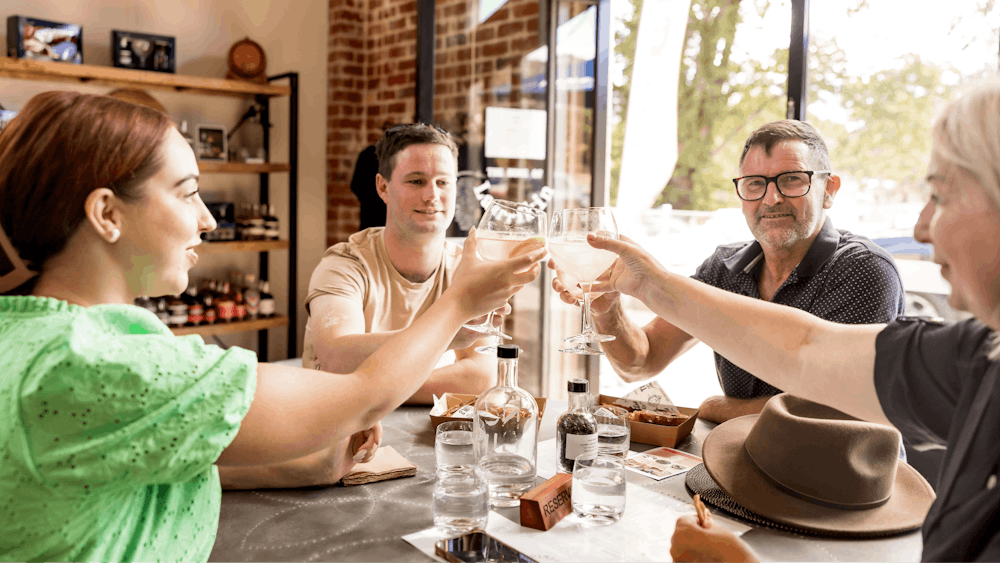 A group of people sitting around a table, raising their glass in a toast