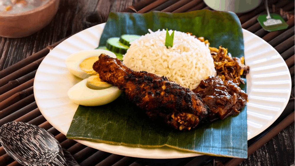 Nasi lemak with sambal, anchovies, peanuts, egg, cucumber and fried chicken.