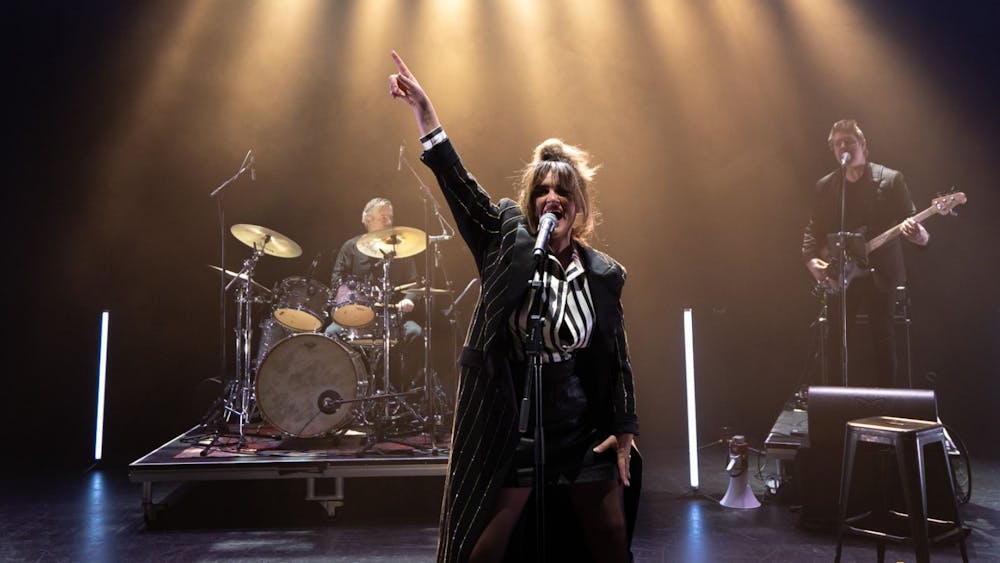 The star of Amplified on stage with a full rock band in the background