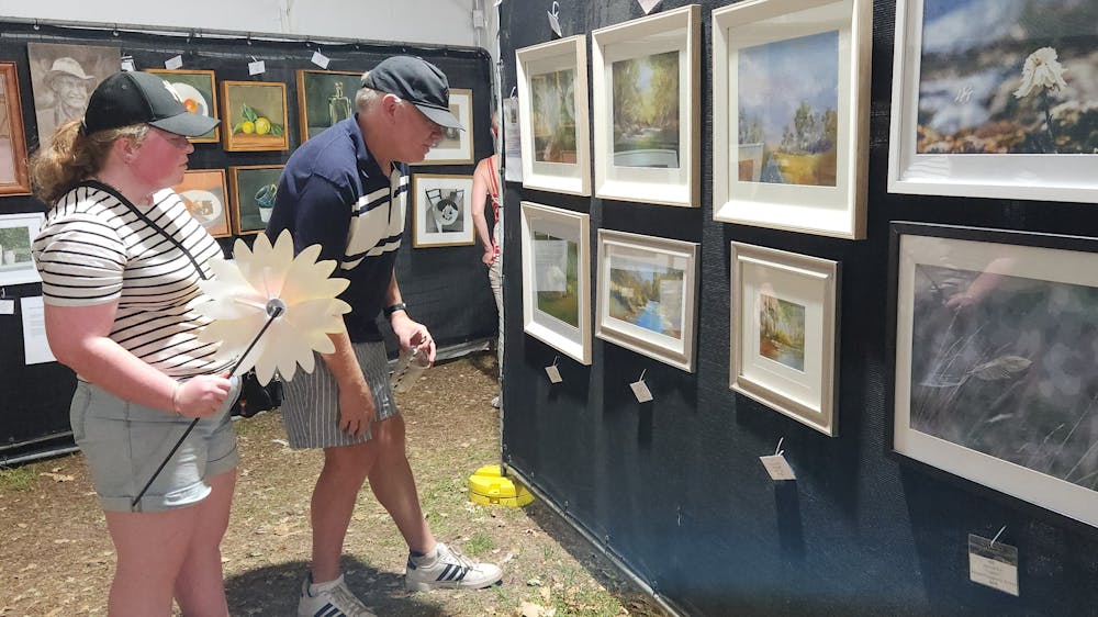 A woman and man looking at artworks displayed on a black wall