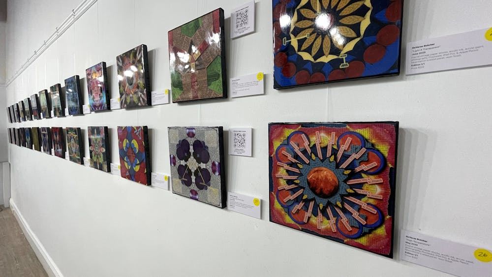 Two rows of artworks aligned in straight lines on the wall of the gallery.