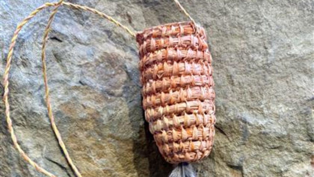 Woven basket with cord straps and feather detail.