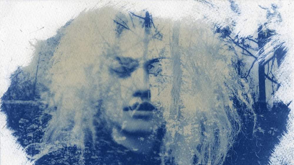 Blue and white cyanotype portrait of a person with shoulder-length white hair