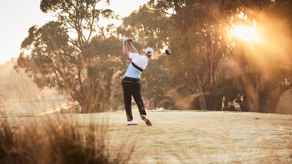 Man mid-swing on golf course
