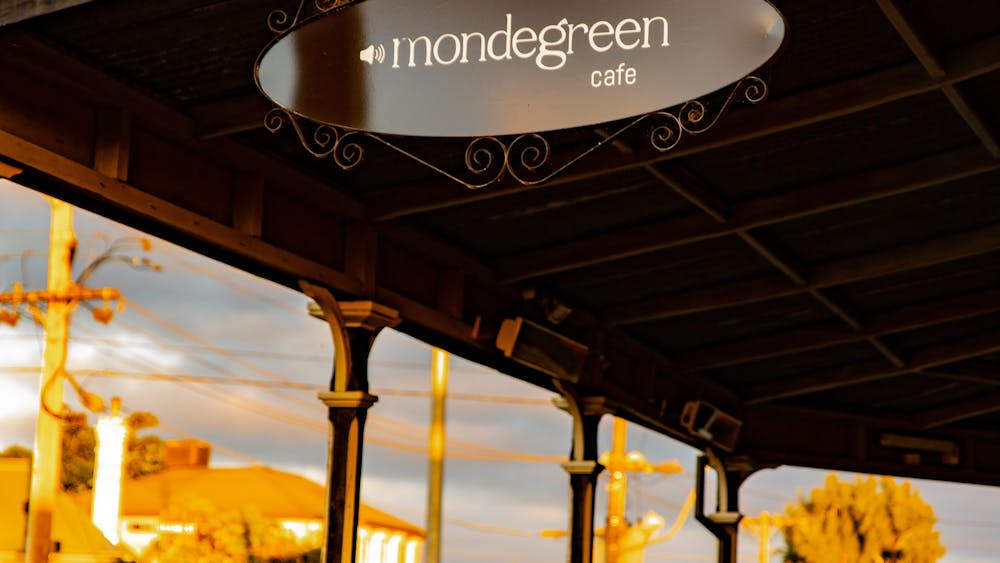 Oval sign of Mondegreen Cafe's logo under the front veranda.