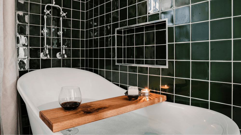 Bathroom with green tiles and clawfoot tub and wine glass
