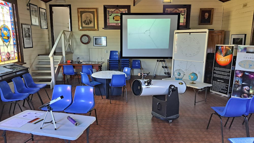 A room with table chairs, a telescope, whiteboard and screen.