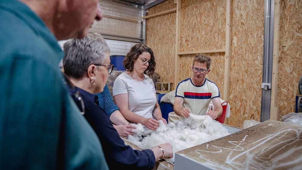 4 people at the carder filling it up with fibre