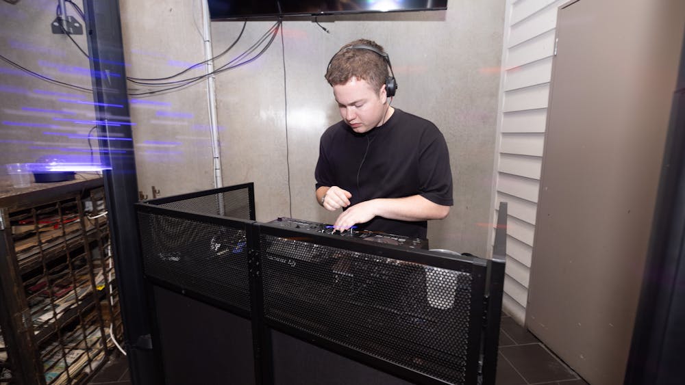 DJ wearing headphones mixing music behind a booth inside Freight Bar during a party event.