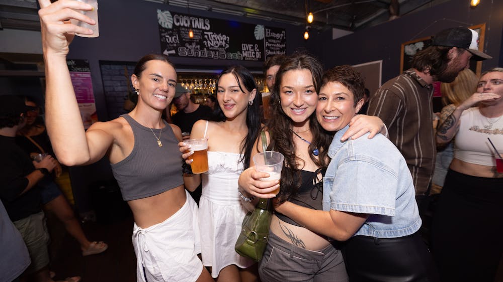 Group of women smiling and holding drinks inside Freight Bar during a Labour Day Eve party.