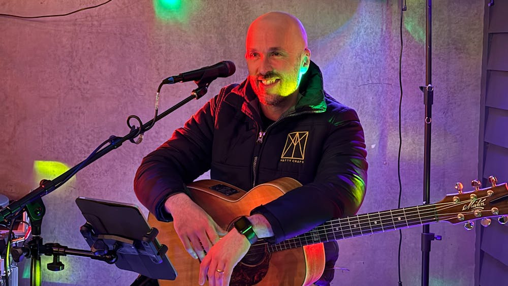 Musician seated with acoustic guitar performing at Freight Bar.