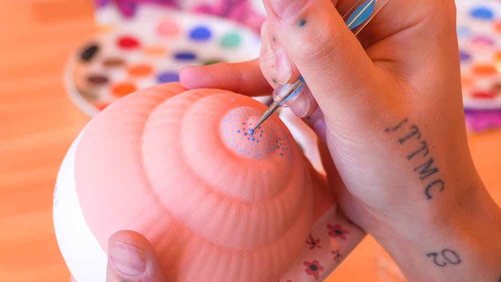A close up of someone painting a snail shell
