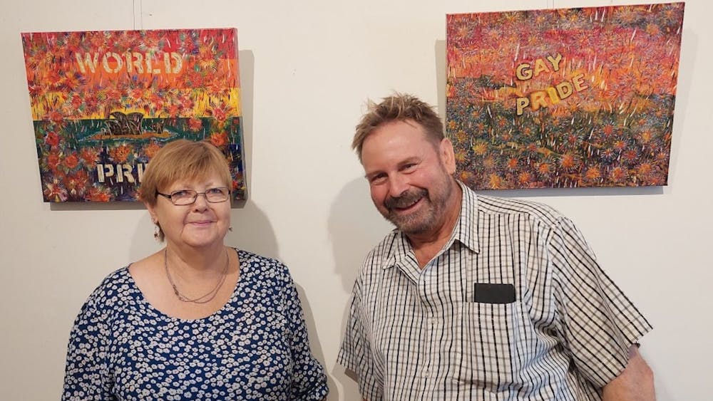 Juliette and Bill are featured infront of Bill's colorful World Pride paintings.   Bill's