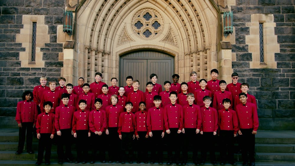 The Australian Boys Choir performing squad wear red jackets standing outside a cathedral