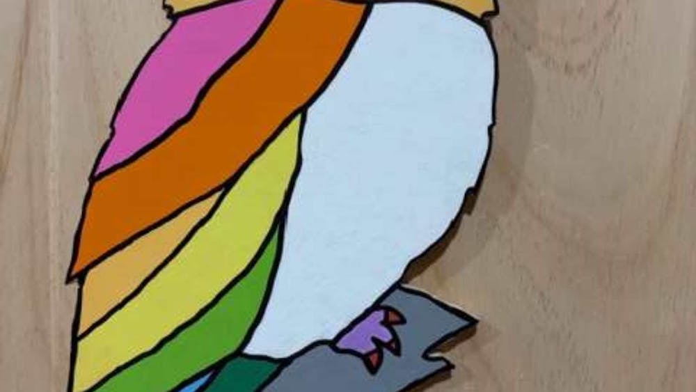 Brightly painted wood cut owl on a wooden bacground.