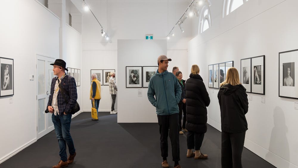 People in an art gallery looking at black and white photographs by Robert Mapplethorpe