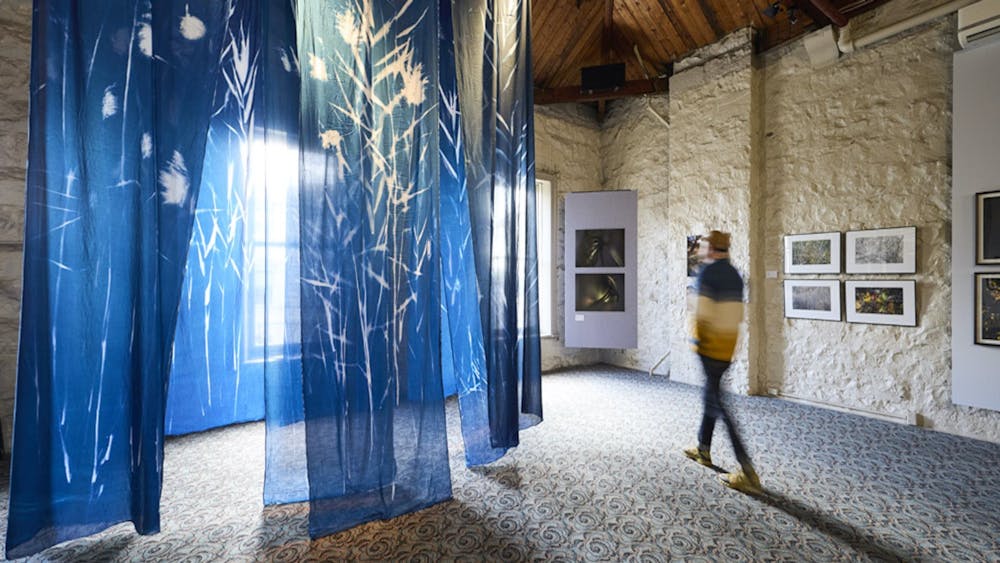Person inside a heritage building with a hanging sculpture of cyanotype prints on fabric