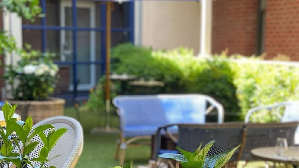 Outdoor restaurant seating area with white and brown mesh chairs, round tables, wicker planter,