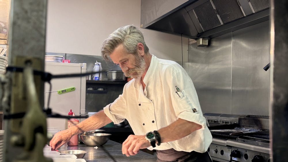 A chef carefully plating food in the professional kitchen at the Courthouse Hotel.