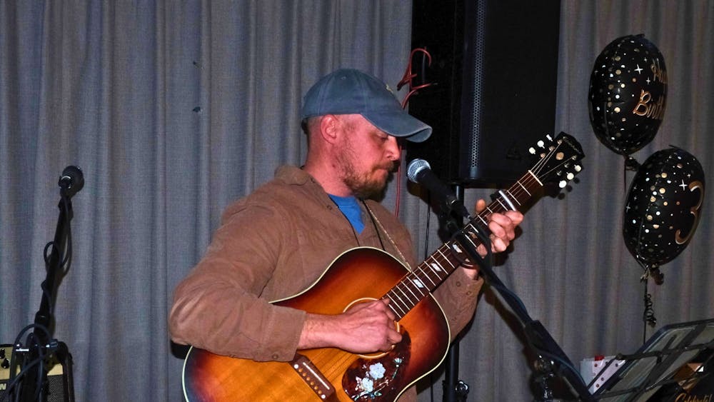 Musician performing live with an acoustic guitar at the Courthouse Hotel birthday event.