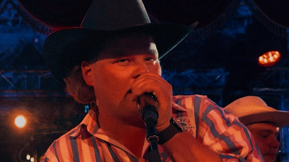 Singer Bottle-O Bill performing live on stage with a microphone at the Courthouse Hotel birt