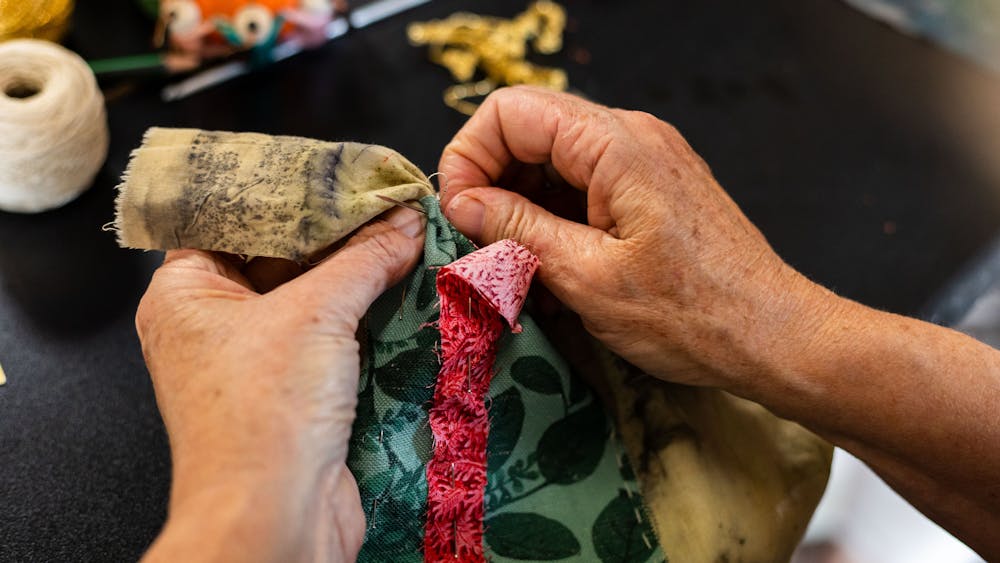 a person's hands showing them stituching materials