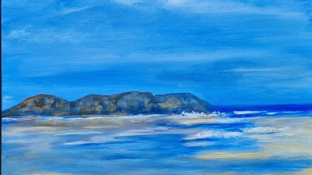 tranquil beach scene with Summer blue sky rocks and sand in the foreground