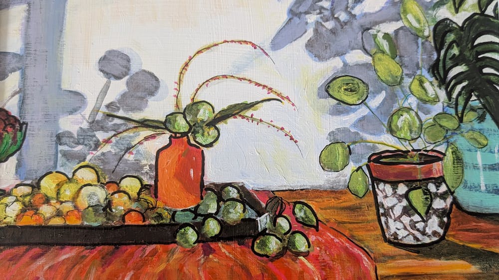 red clothed table with a plant and fruit and flowers in a vase and beautiful shadows on the wall.