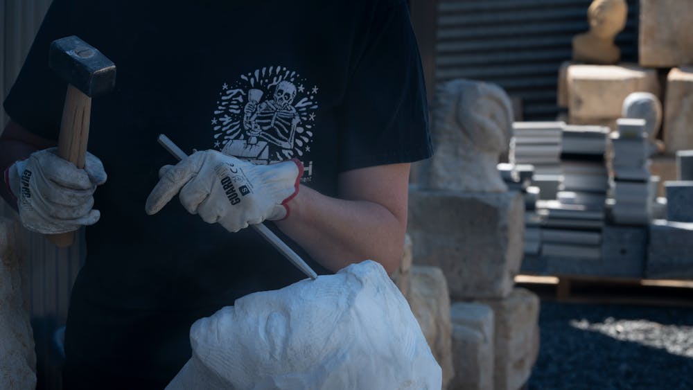 person using stone carving tools to work with marble