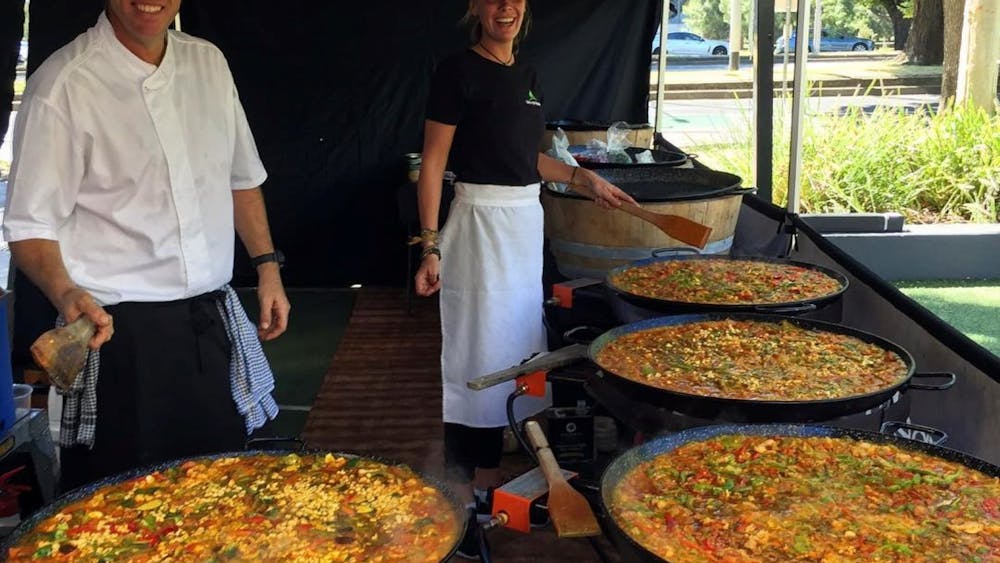 man and woman cooking and serving Melbourne Paella