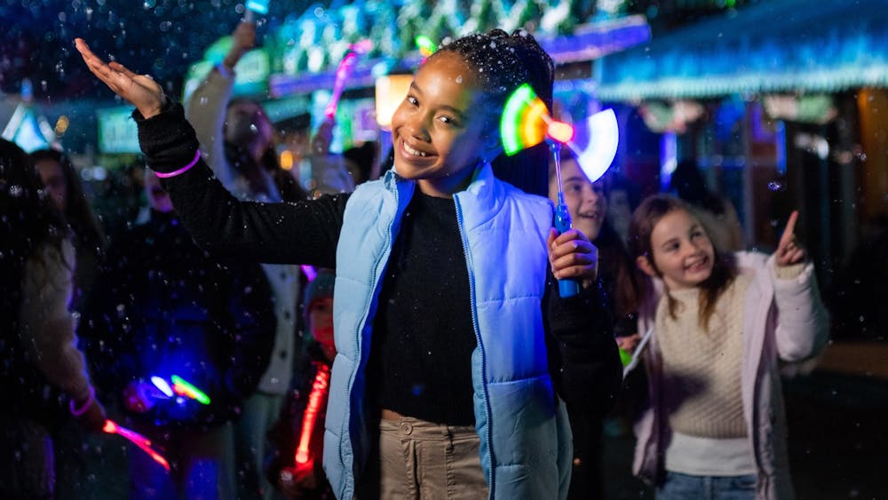 Girl smiling to camera holding our her hand to catch fake snow flakes