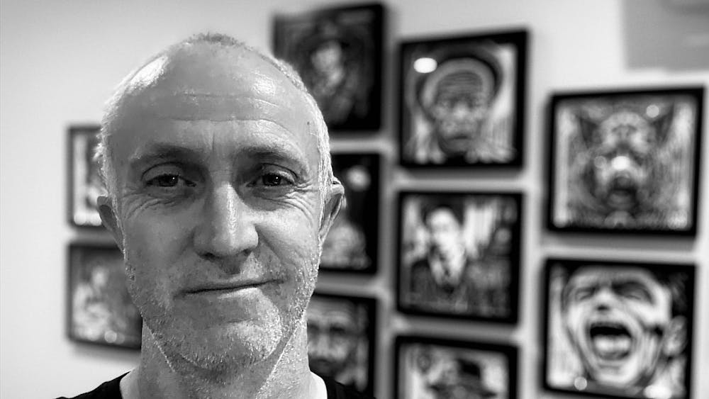 Black & White photo of Colin infront of his works