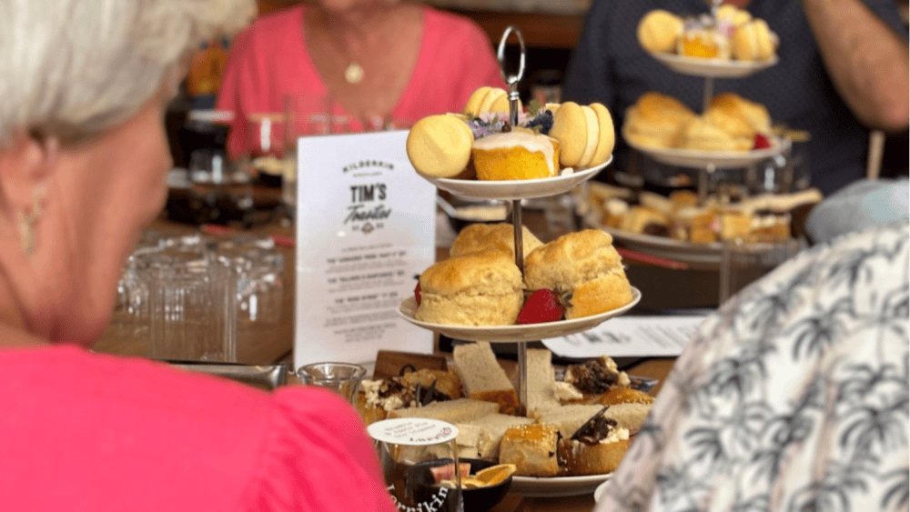 A tower of sweet and savoury treats in the middle of a table that is surrounded by people
